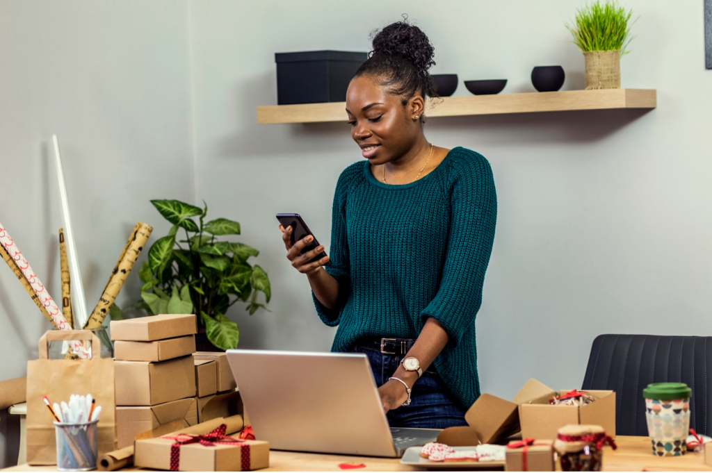 KRA eTIMS Compliant POS in Kenya: A black woman working on phone with their laptop surrounded by inventory