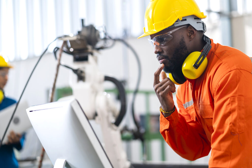 manufacturing erp in kenya: portrait of engineer technician wearing uniform looking at computer screen